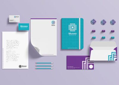 branding empresarial: Identidad visual: tarjetas de presentación, cuaderno de notas, lápices, sobres, pines, libreta con identidad visual del museo Mazunte, todos respetando los colores aqua y morado, utilizando la imagen del logotipo como textura.