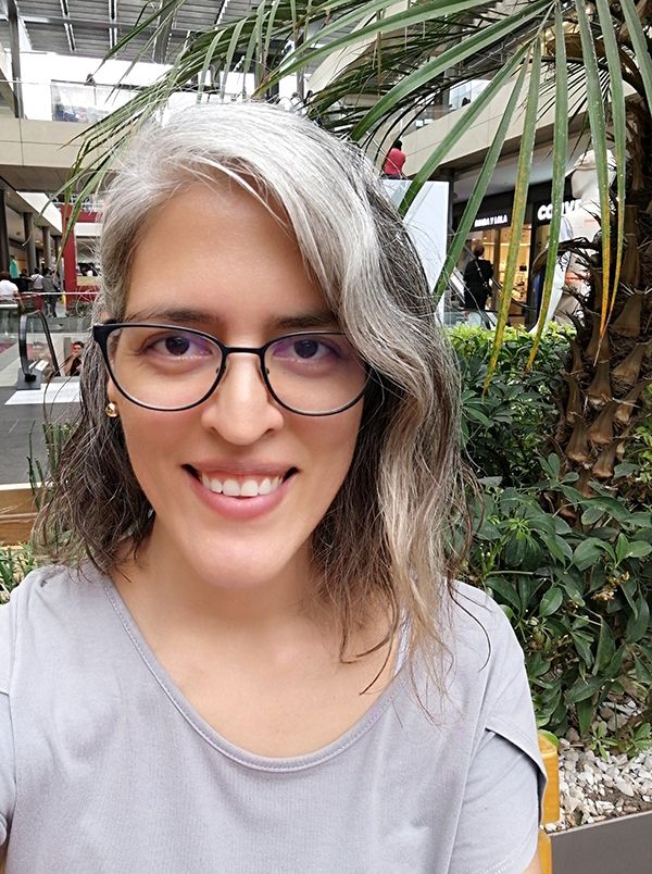 Mónica González, Coordinadora de Nalé Diseño, sonriente en un jardín, con lentes modernos.