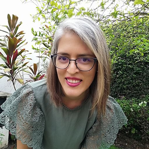 Mónica González, Coordinadora de Nalé Diseño, sonriente en un jardín, con lentes modernos.