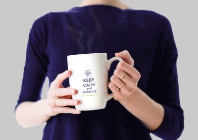 Ejemplo de diseño de identidad visual: en la imagen se muestra una taza blanca con isotipo y leyenda “Keep calm and meditate” con tipografía Artico Soft, todo de color morado sabio. Hasta abajo se colocó una franja delgada color ocre.